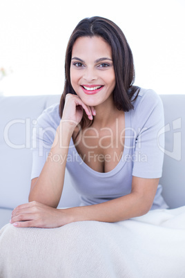 Smiling beautiful brunette sitting on the couch