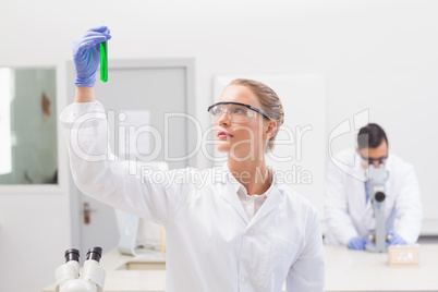 Scientist examining green precipitate in tube