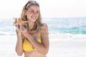 Smiling pretty blonde in bikini holding a starfish