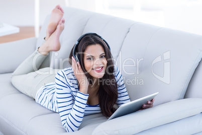 Smiling beautiful brunette listening music while using her table