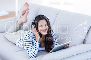 Smiling beautiful brunette listening music while using her table