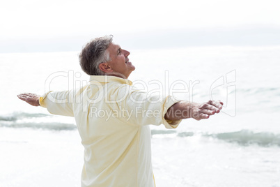 Smiling man standing by the sea arms outstretched
