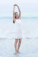 Smiling blonde in white dress standing by the sea