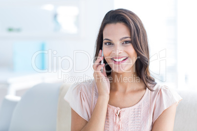 Smiling beautiful brunette relaxing on the couch and speaking on