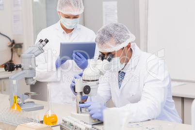 Scientists using tablet pc and microscope