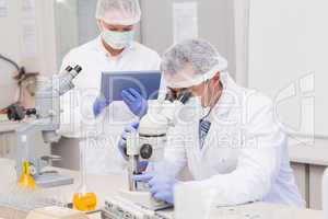 Scientists using tablet pc and microscope