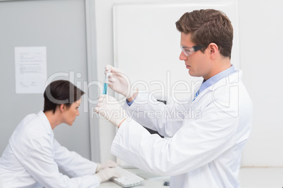 Scientists working attentively with test tube and computer