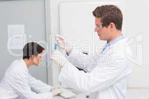 Scientists working attentively with test tube and computer