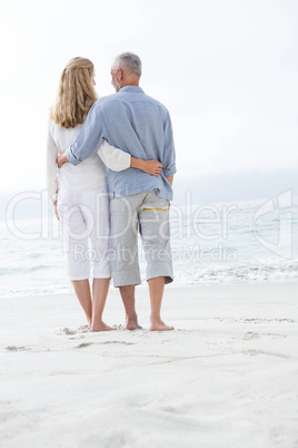 Happy couple hugging each other and looking at the sea