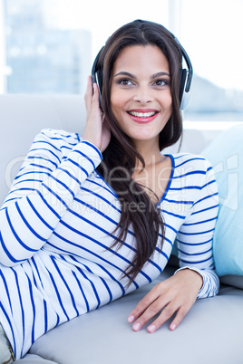 Smiling beautiful brunette relaxing on the couch and listening m