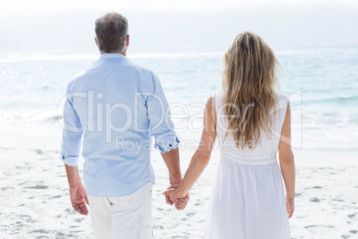 Happy couple standing by the sea and holding hands