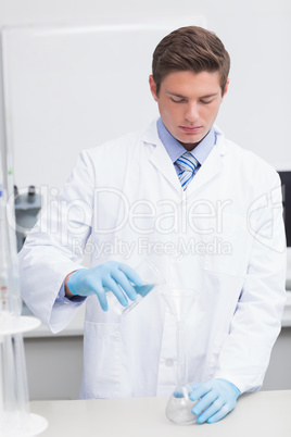 Scientist pouring chemical product in funnel