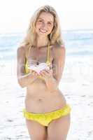 Smiling pretty blonde holding a seashell