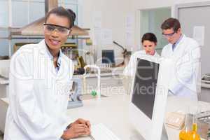 Happy scientist smiling at camera while colleagues working toget