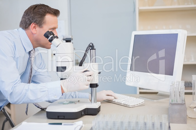 Scientist using computer and microscope