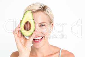 Pretty woman covering her eye with an avocado
