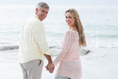 Happy couple standing by the sea and holding hands