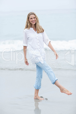 Smiling blonde walking by the sea and looking at camera