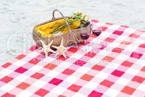 Picnic basket with glasses of red wine and starfishes on a blank