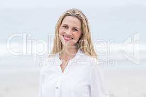 Smiling blonde standing by the sea and looking at camera