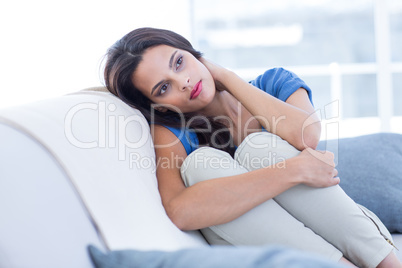 Thoughtful beautiful brunette sitting on the couch