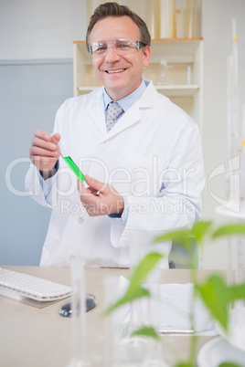Scientist smiling at camera holding tube