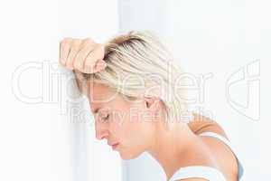 Sad blonde woman with her head on wall