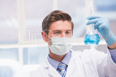 Scientist examining beaker with blue fluid