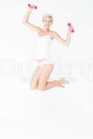 Happy woman jumping and holding dumbbells