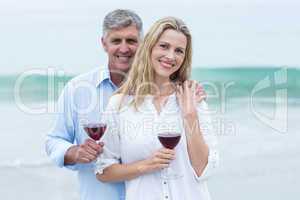 Happy couple smiling at camera and holding a glass of red wine