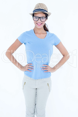 Happy brunette woman wearing hat with hands on hips