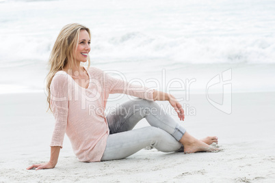 Smiling pretty blonde relaxing on the sand