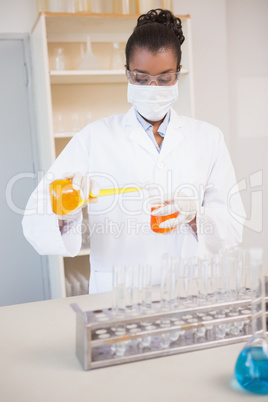 Concentrated scientist pouring orange fluid
