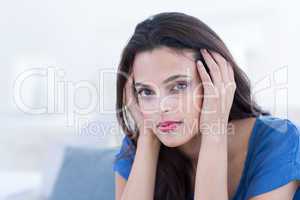 Thoughtful beautiful brunette sitting on the couch