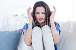 Worried beautiful brunette sitting on the couch