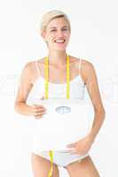 Happy woman holding scales smiling at camera