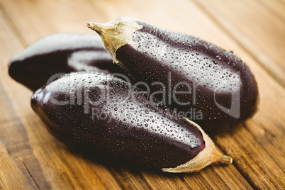 Three aubergines on wooden board