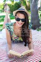 Smiling beautiful brunette lying and reading a book
