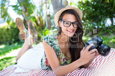 Smiling beautiful brunette lying on the blanket and taking pictu