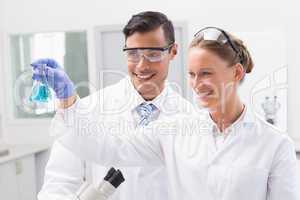 Smiling scientists looking at beaker