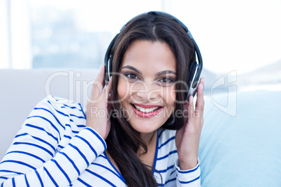 Smiling beautiful brunette relaxing on the couch and listening m