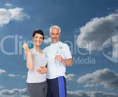 Composite image of happy fit couple with dumbbell and water bott