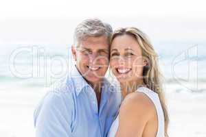 Happy couple standing by the sea and smiling at camera