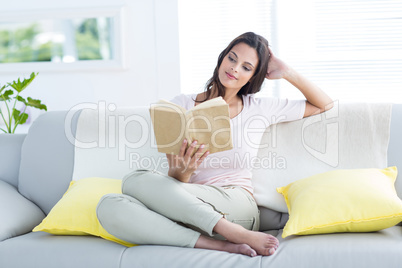 Smiling beautiful brunette relaxing and reading a book on the co