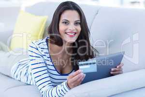 Smiling beautiful brunette doing online shopping on the couch