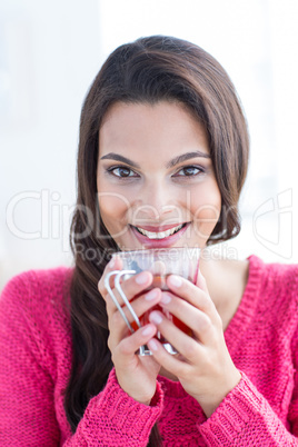 Smiling beautiful brunette relaxing on the couch and holding cup