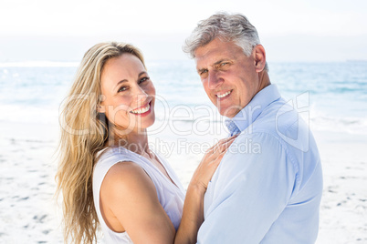 Happy couple standing by the sea and smiling at camera