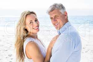 Happy couple standing by the sea and smiling at camera