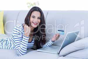 Smiling beautiful brunette doing online shopping on the couch