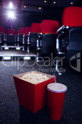 Empty rows of red seats with pop corn and drink on the floor